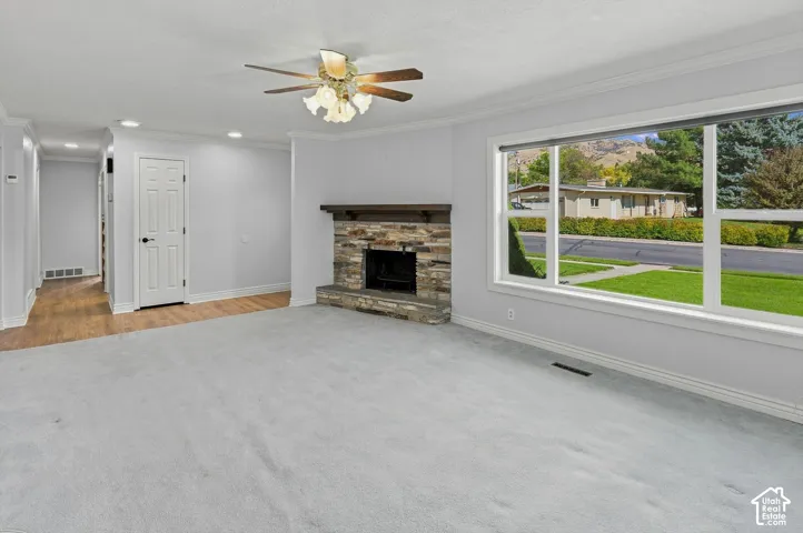 Spacious living area featuring a stone fireplace with a wood mantle, a large picture window, and recessed lighting