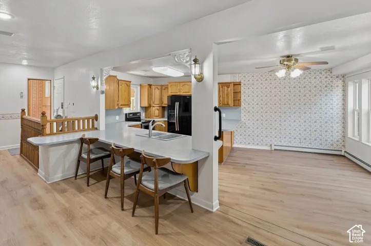 Kitchen featuring wood cabinetry, a double basin sink, and a black refrigerator