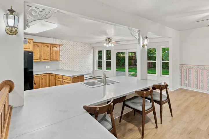 Kitchen featuring a double basin sink, light wood-finish cabinetry, and a peninsula countertop