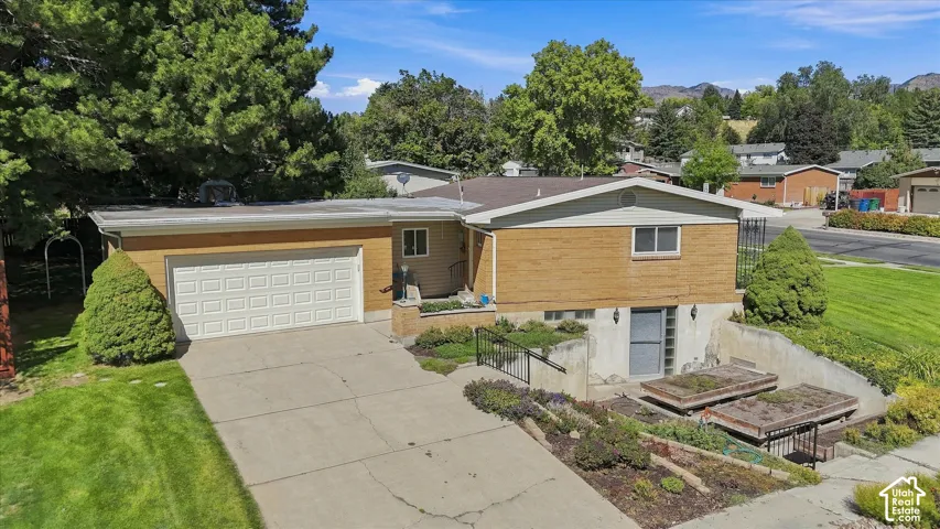 Split-level residence featuring a brick and siding exterior, an attached garage, and a concrete driveway