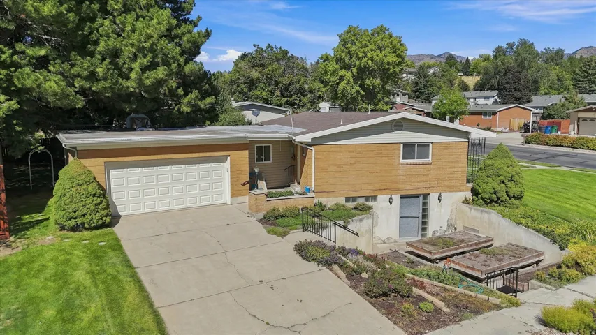 Split-level residence featuring a brick and siding exterior, an attached garage, and a concrete driveway