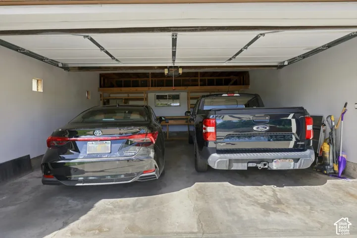 Two-car garage featuring a concrete floor, white painted walls, and built-in shelving