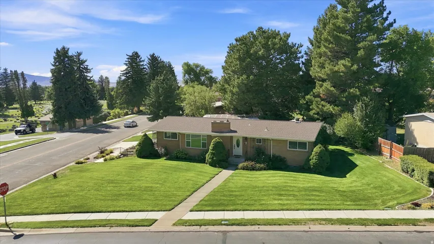 Single-story residence featuring a traditional brick exterior, gabled roof, and a mature landscaped yard with a concrete pathway