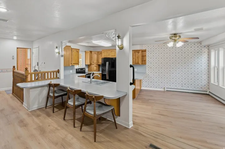 Kitchen featuring wood cabinetry, a double basin sink, and a black refrigerator