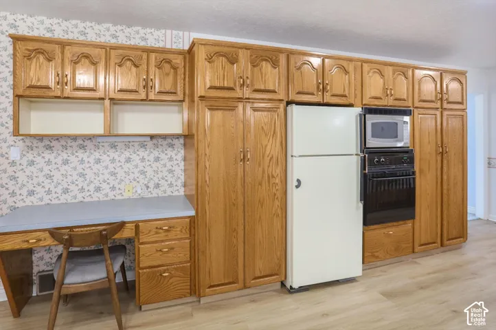 Wood-finish cabinetry, built-in desk with laminate countertop, integrated wall oven, and microwave