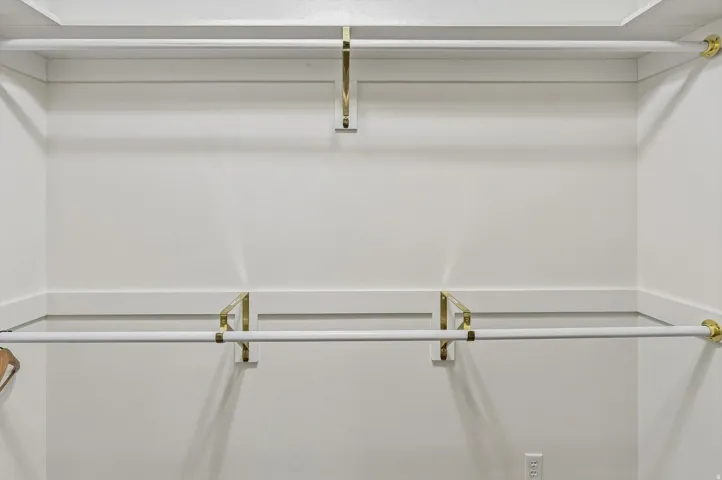 White closet system featuring gold-finish hardware and multiple hanging rods