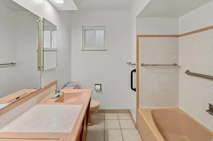 Bathroom with built-in vanity, integrated sink, and tiled countertop