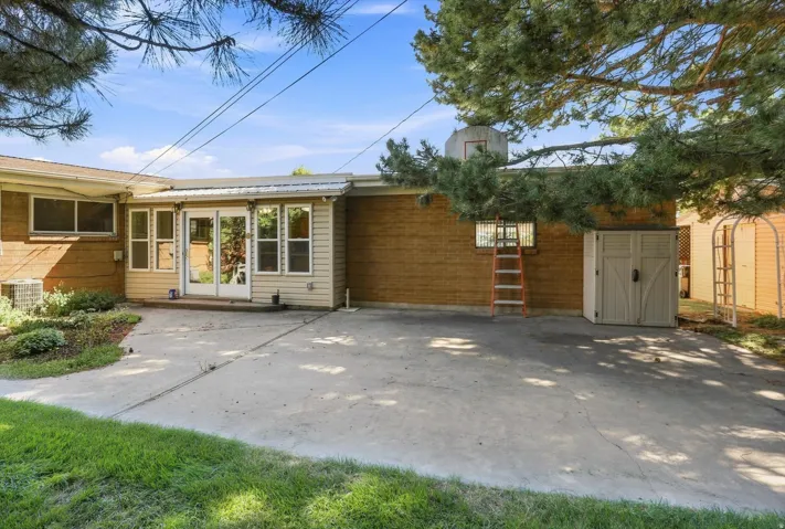 Expansive concrete patio with direct access to an enclosed sunroom featuring multiple windows and a glass-paneled door