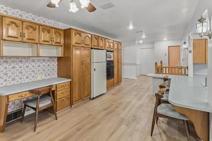 Light wood-finish flooring, wood cabinetry, built-in desk, built-in oven, and recessed lighting