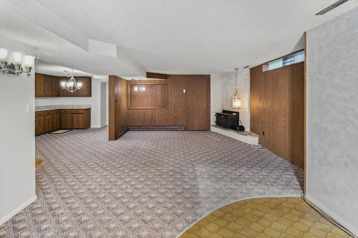 Lower-level space with patterned carpeting, built-in wood cabinetry, and a brick fireplace
