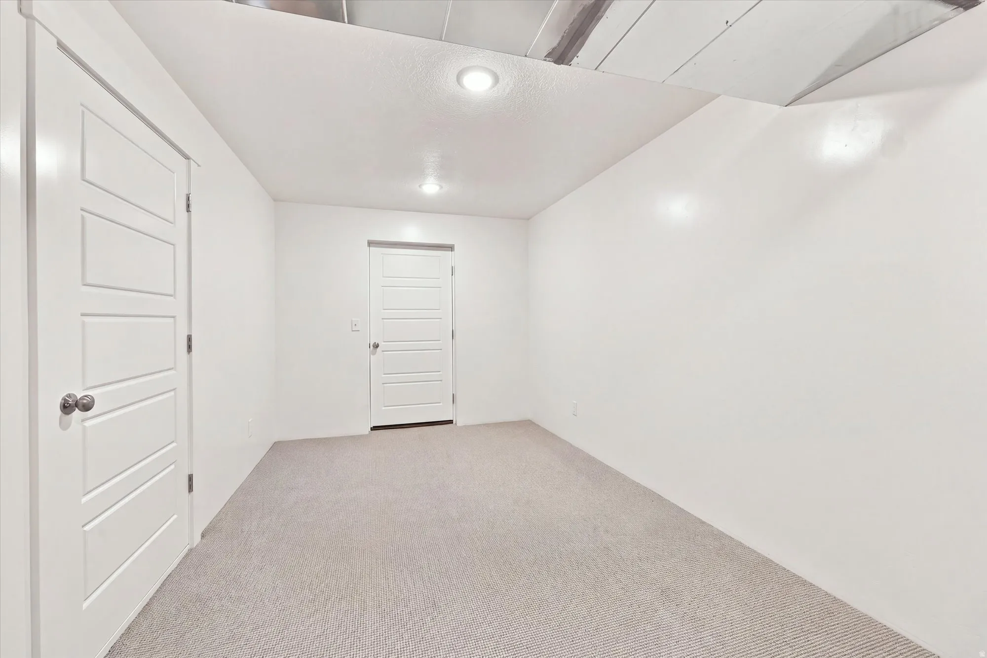 Neutral-toned carpeted flooring, white walls, and recessed lighting