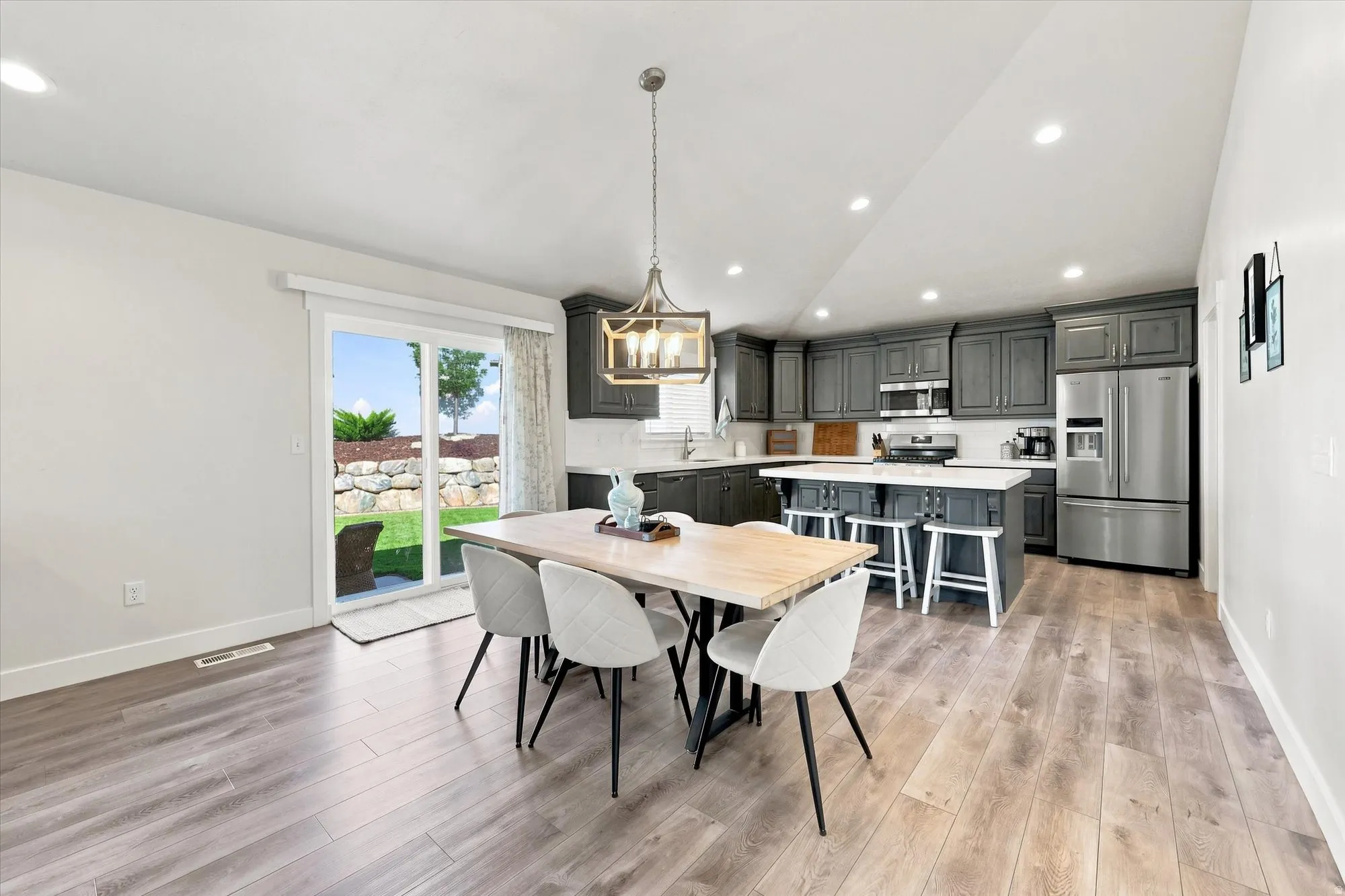 Open-concept kitchen featuring gray cabinetry, stainless steel appliances, and a central island with bar seating