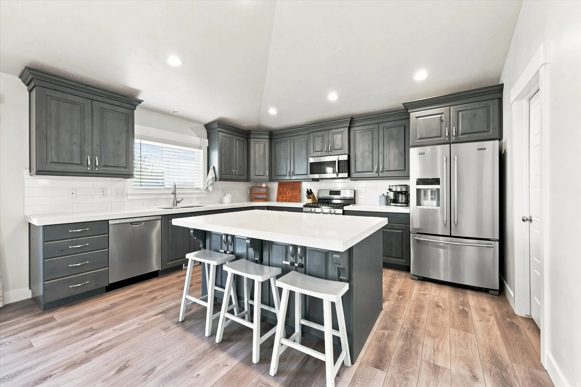 Kitchen featuring dark wood-finish cabinetry, white countertops, stainless steel appliances, and wood-finish flooring