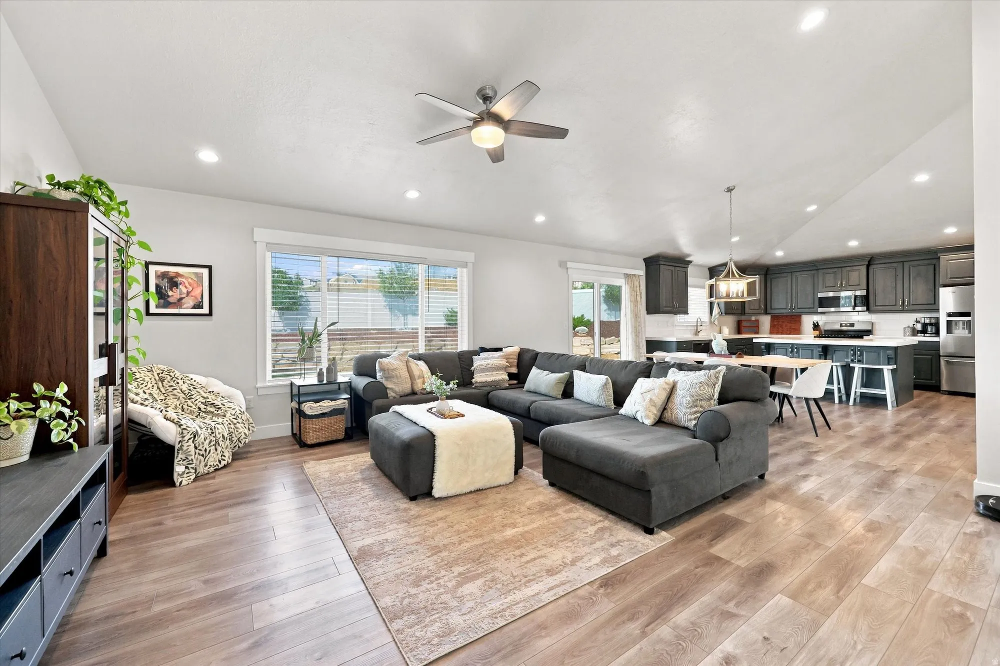 Open-concept living space with wood-finish flooring, a contemporary ceiling fan, and recessed lighting