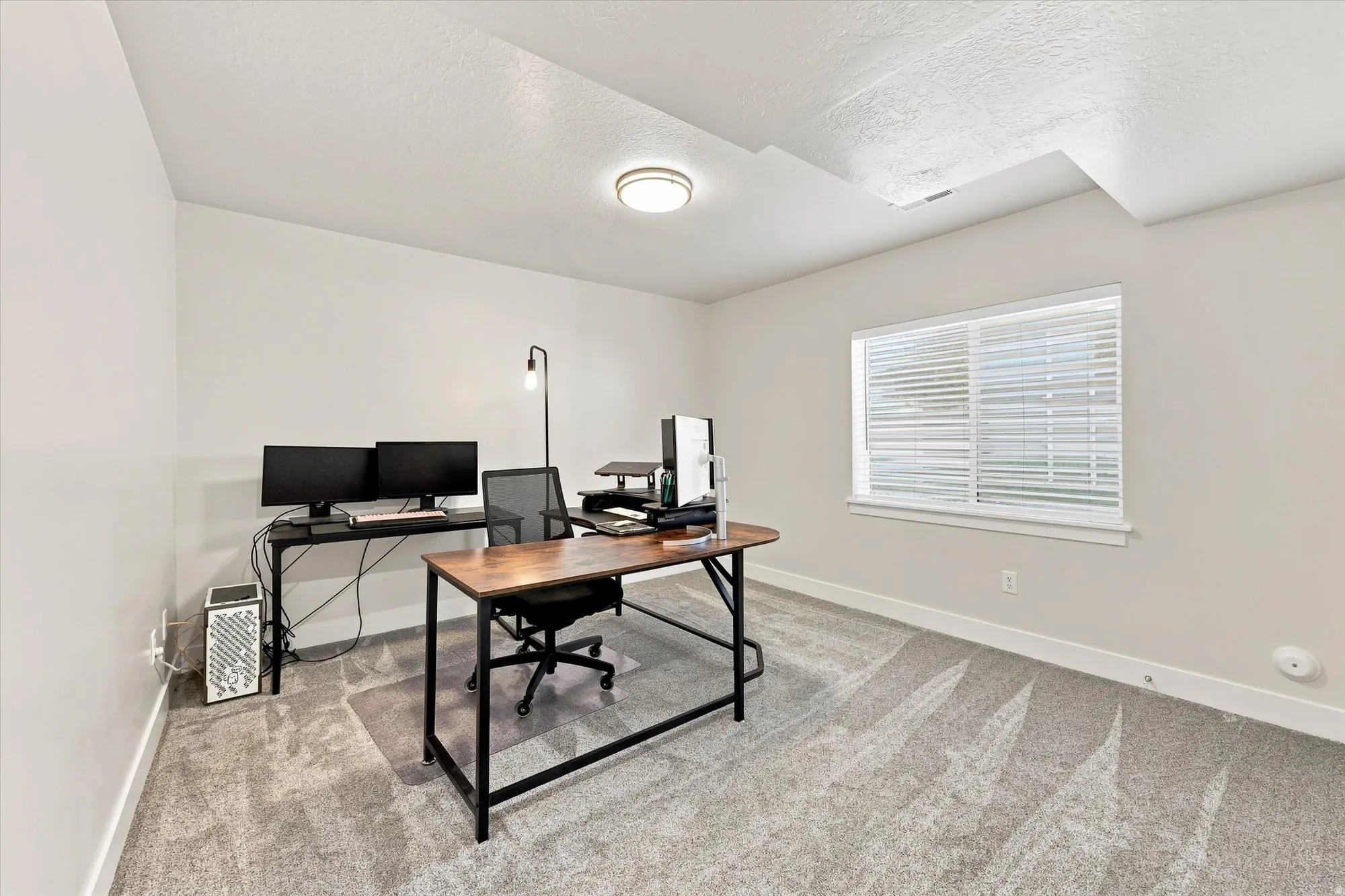Recessed ceiling light, neutral wall paint, single window with blinds, light-toned carpet flooring, white trim