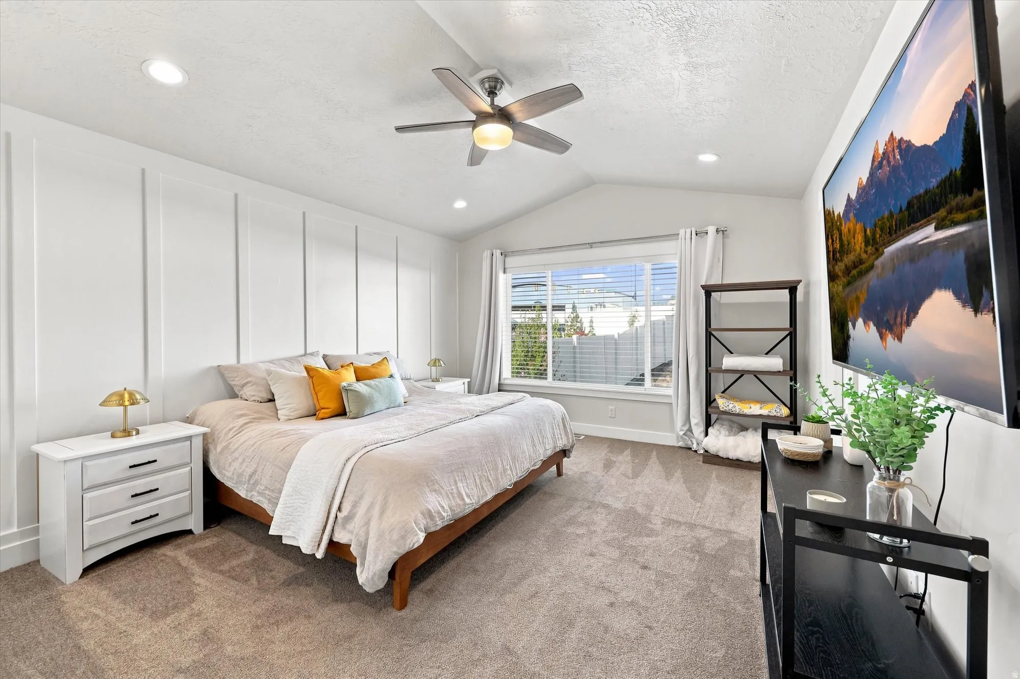 Vaulted ceiling with a ceiling fan, recessed lighting, accent wall with vertical paneling, and a large window with blinds