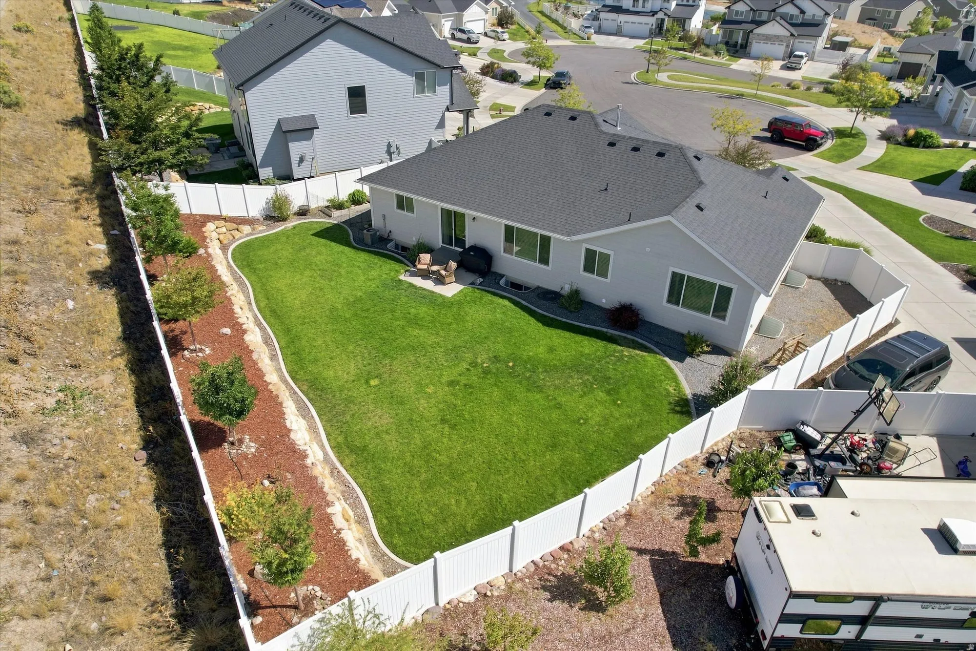 Expansive lawn area, white privacy fencing, rear patio, and established landscaping