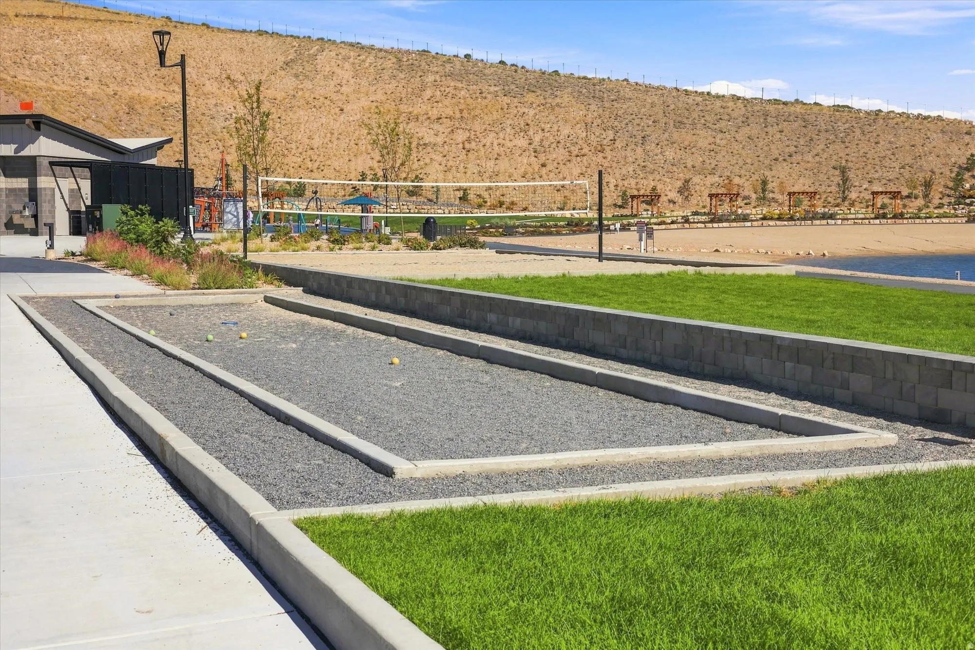 Bocce ball court, manicured lawn, concrete pathway, gravel bed, and stone retaining wall