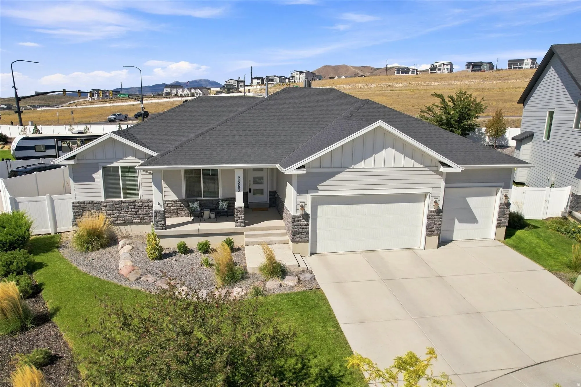 Contemporary ranch-style residence featuring a prominent two-car garage, partial stone facade, and a covered front porch