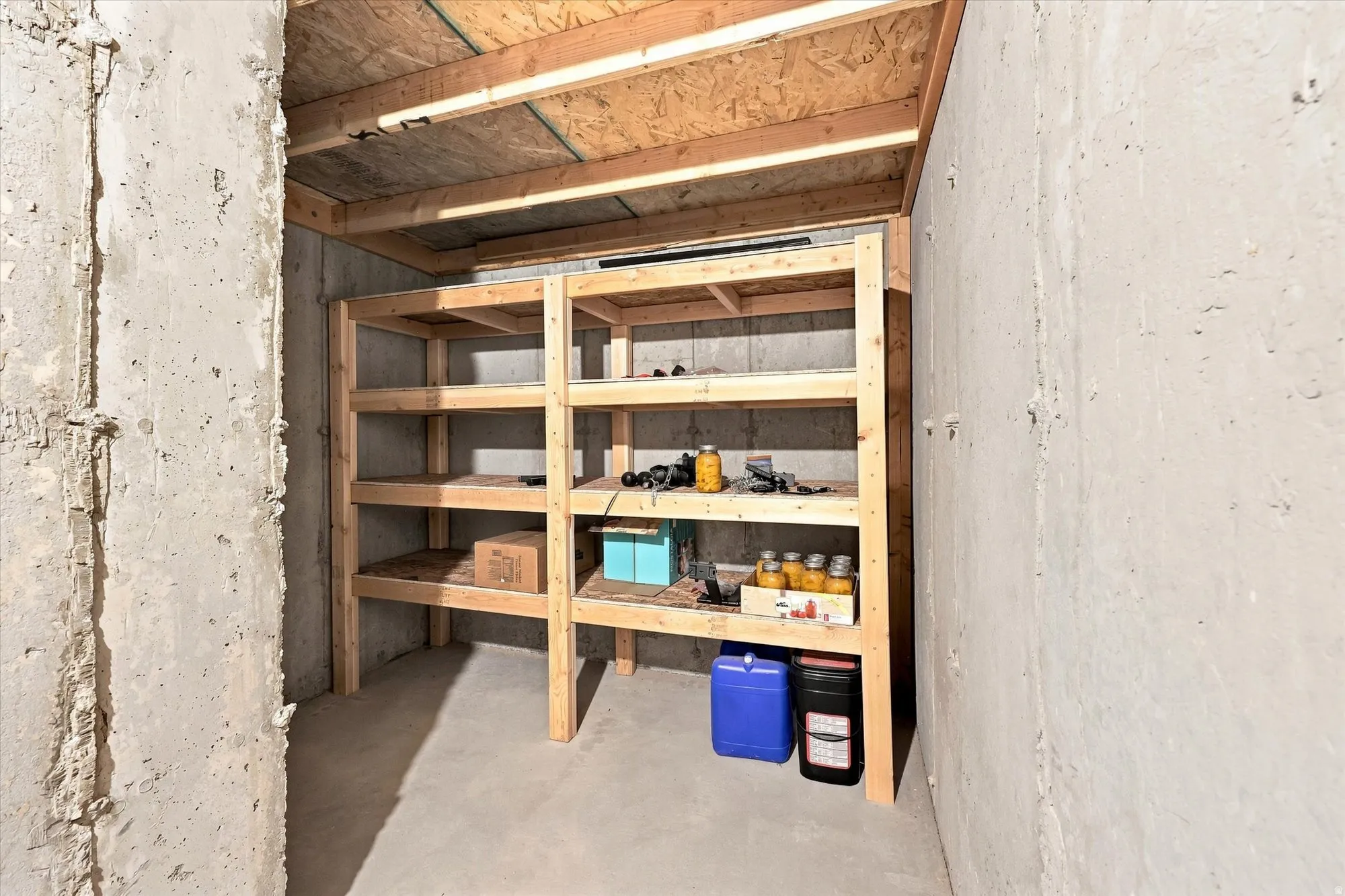 Concrete walls with exposed wood ceiling beams and built-in wood shelving