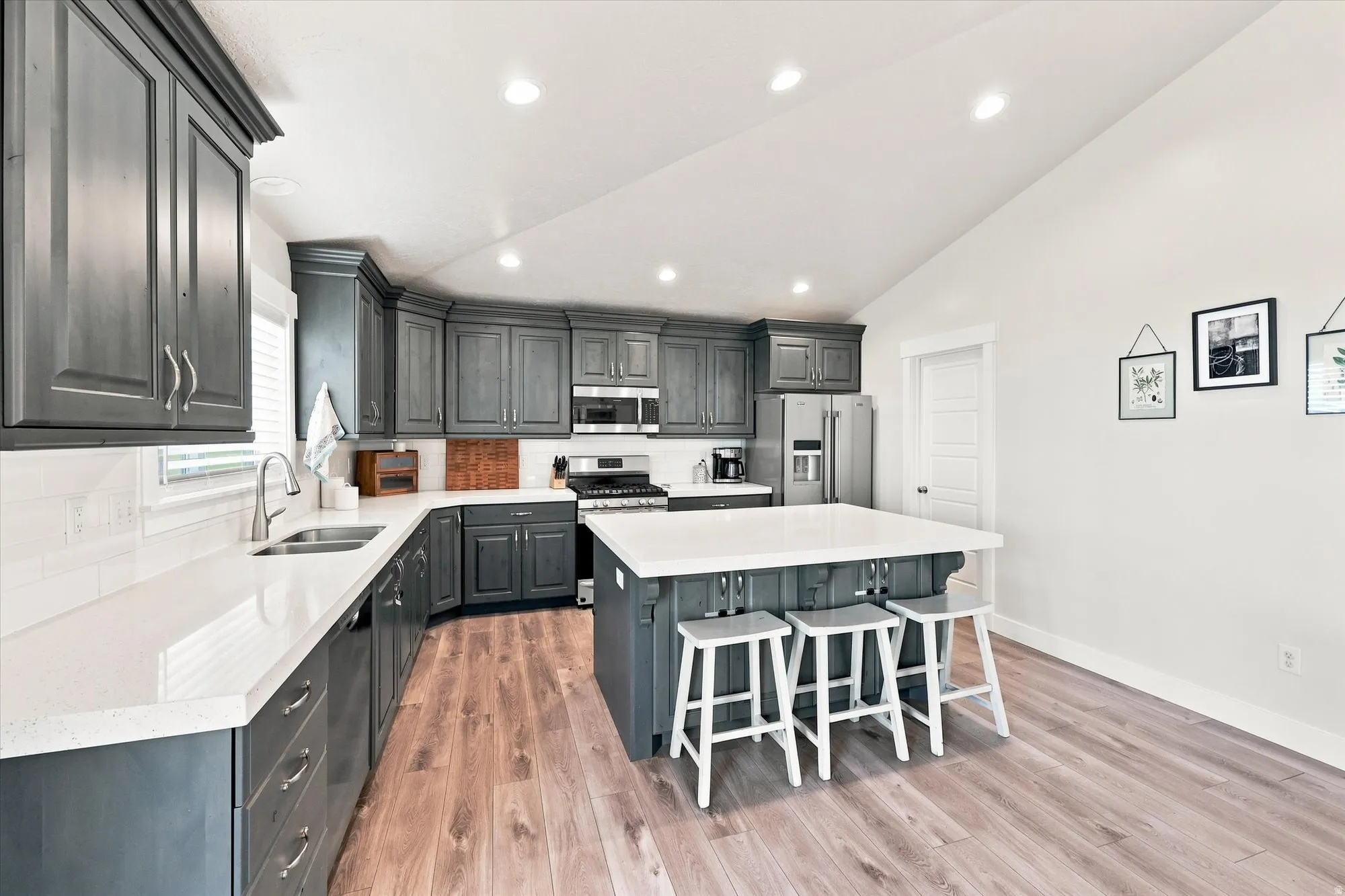 Kitchen featuring wood-finish flooring, recessed lighting, dark cabinetry, light countertops, and a center island