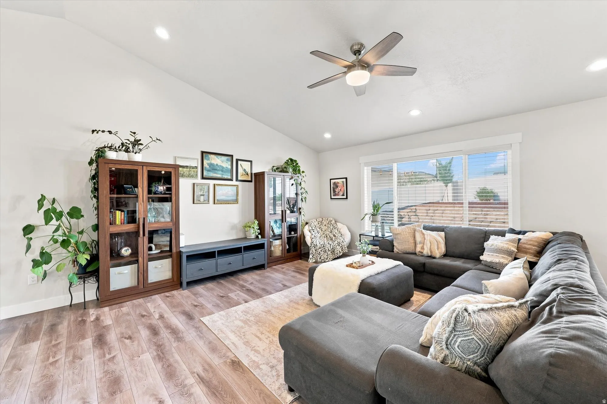 Vaulted ceiling, recessed lighting, wood-finish flooring, ceiling fan, and large windows