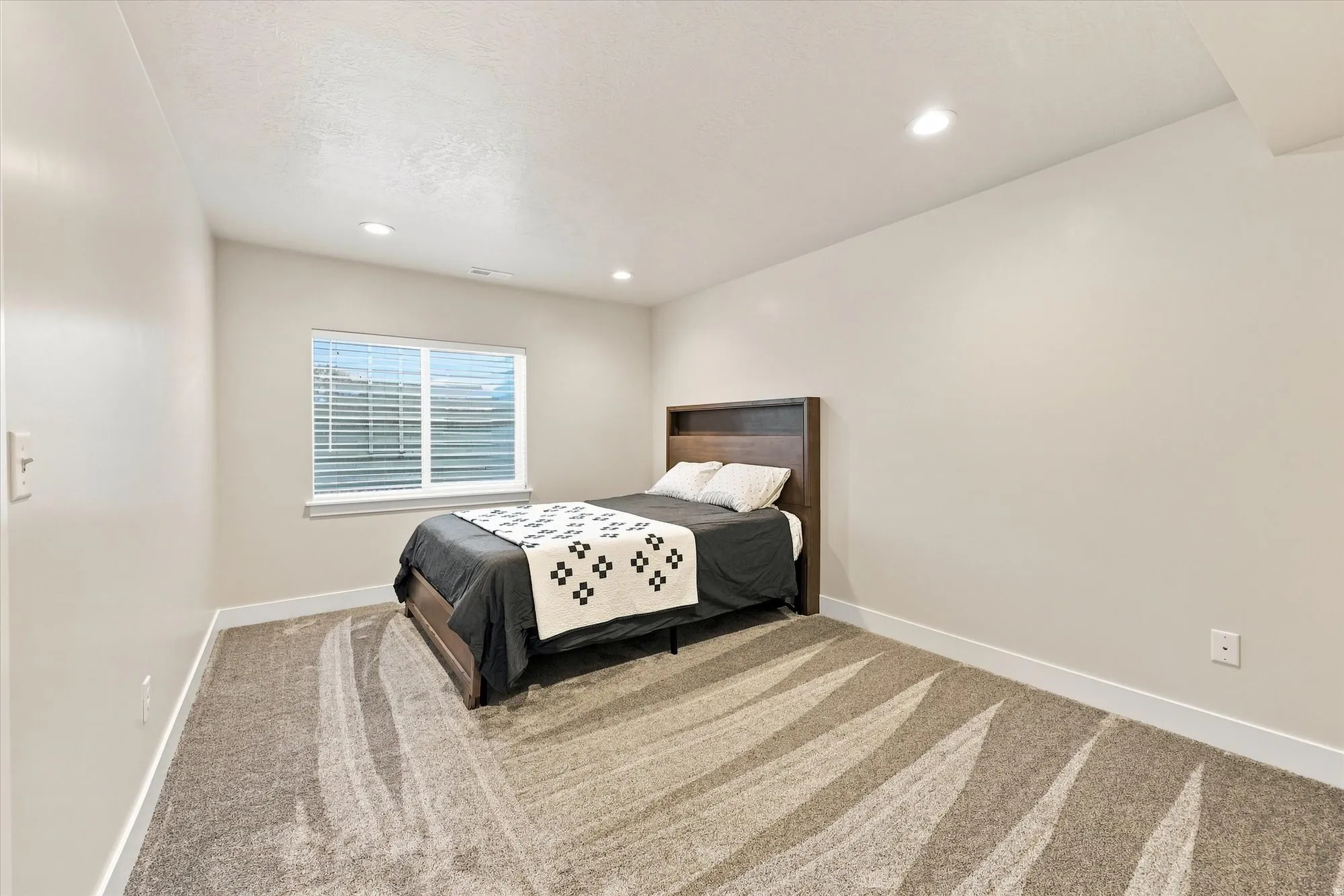 Recessed lighting, light-toned walls, and patterned carpet
