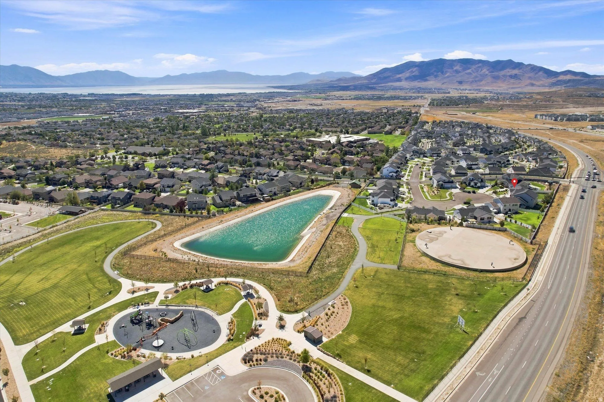 Expansive residential area featuring a prominent lake, a large park with playground equipment, and a sports field