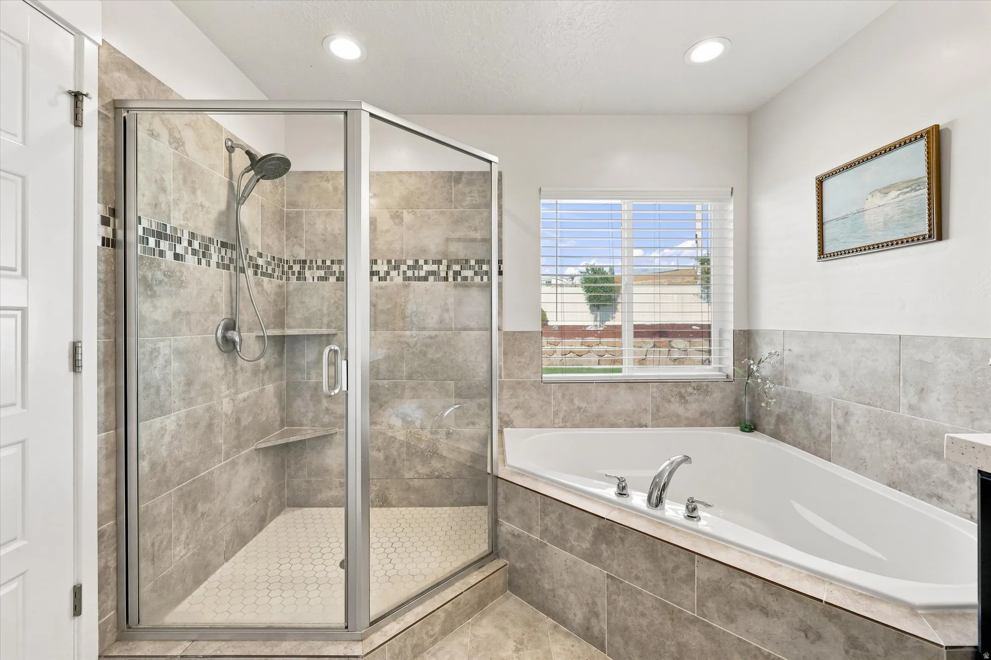 Walk-in shower with tile surround and mosaic accent, built-in shelving, and a glass enclosure
