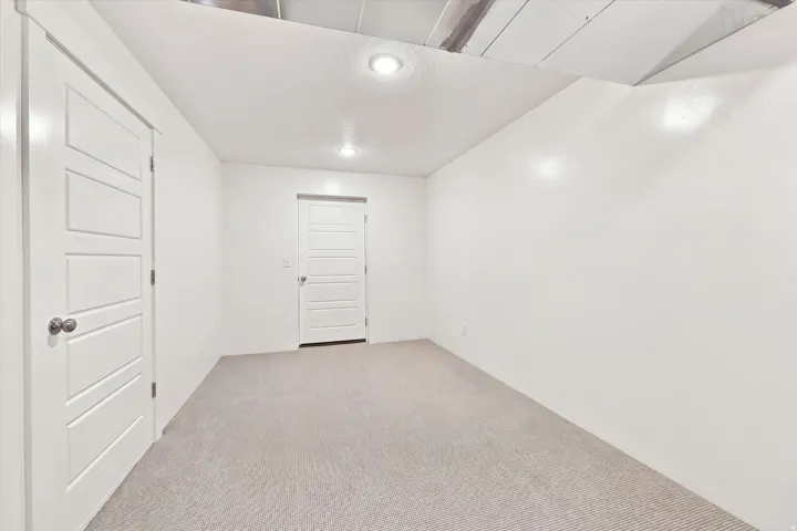 Neutral-toned carpeted flooring, white walls, and recessed lighting