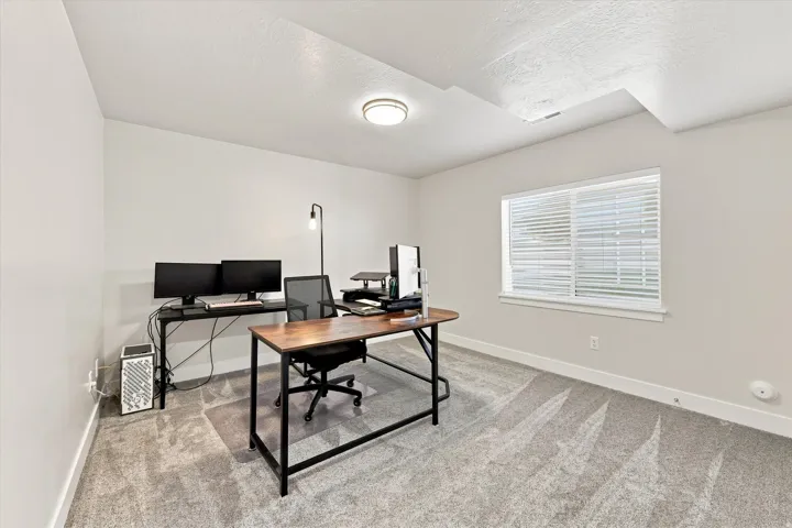 Recessed ceiling light, neutral wall paint, single window with blinds, light-toned carpet flooring, white trim