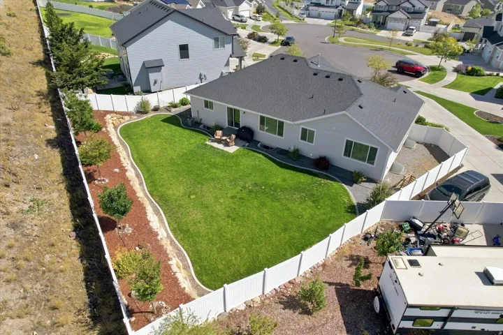Expansive lawn area, white privacy fencing, rear patio, and established landscaping