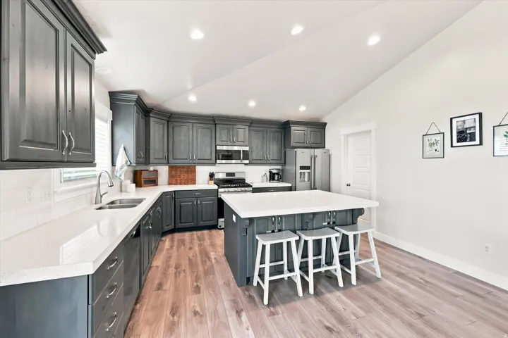 Kitchen featuring wood-finish flooring, recessed lighting, dark cabinetry, light countertops, and a center island