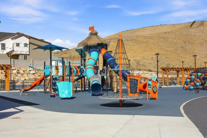 Outdoor play area featuring multiple slides, climbing structures, and protective surfacing