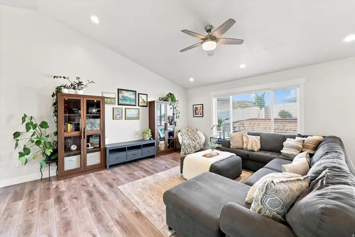 Vaulted ceiling, recessed lighting, wood-finish flooring, ceiling fan, and large windows