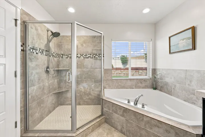 Walk-in shower with tile surround and mosaic accent, built-in shelving, and a glass enclosure