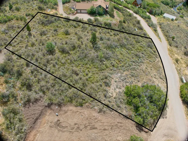 Expansive lot featuring natural vegetation, a partially cleared lower section, and direct access to an unpaved road