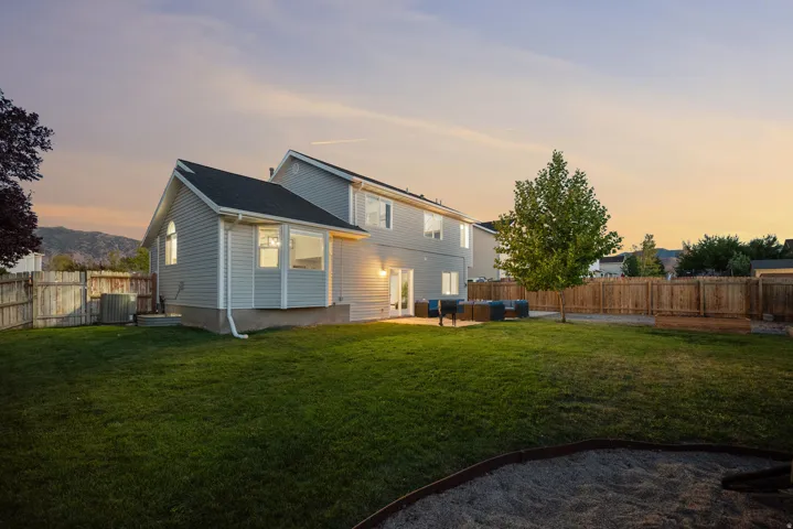 Expansive grassy yard with a privacy fence and mature trees