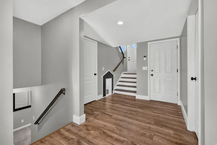 Wood-finish flooring, white paneled doors, recessed lighting, and a modern stair railing