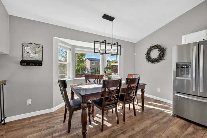 Bay window with multiple panes, wood-finish flooring, and a stainless steel refrigerator