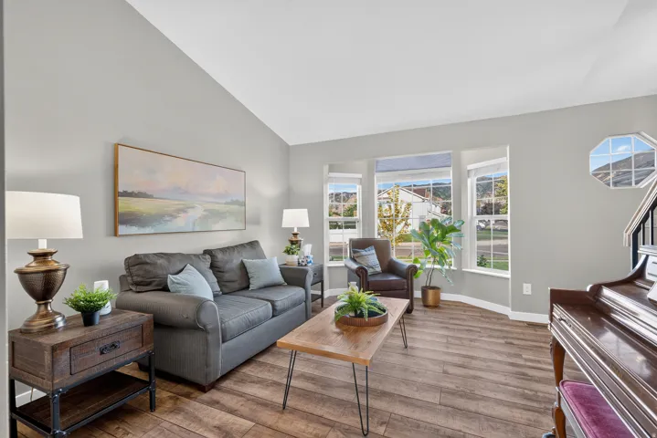 Vaulted ceiling, bay window, wood-finish flooring, staircase with dark banister, and an octagonal window