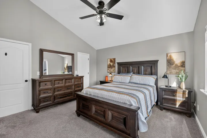 Vaulted ceiling with a ceiling fan, light gray wall paint, and gray carpet flooring