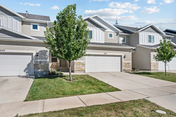 Contemporary townhome exterior with mixed material facade, concrete driveway, attached garage, and manicured lawn