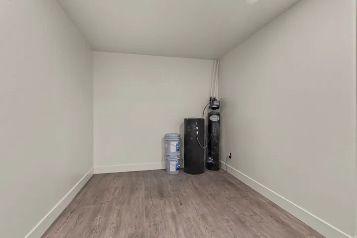 Utility room with wood-finish flooring and a water treatment system