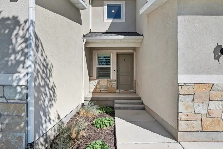 Stucco exterior with stone accent detailing, covered entry, and integrated planter bed