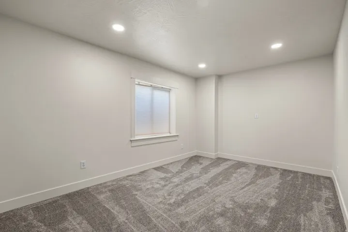 Recessed ceiling lighting, textured wall finishes, window with blinds, and grey carpeting