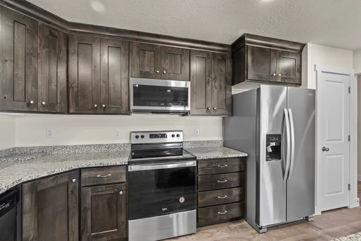 Dark-stained cabinetry, granite-style countertops, stainless steel appliances, and wood-finish flooring