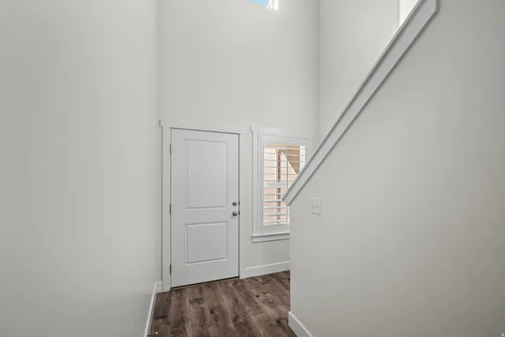 High ceilings with a transom window, wood-finish flooring, white paneled door, and a staircase with a white railing