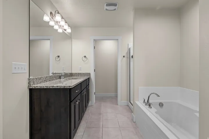 Dual vanity with granite-style countertop, undermount sinks, and dark wood-finish cabinetry