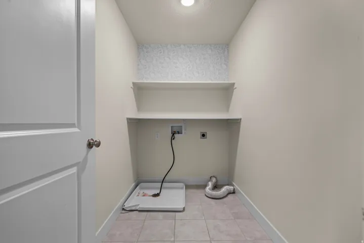 Tile flooring, built-in shelving, paneled door, ceiling-mounted light fixture, and wall-mounted electrical outlets